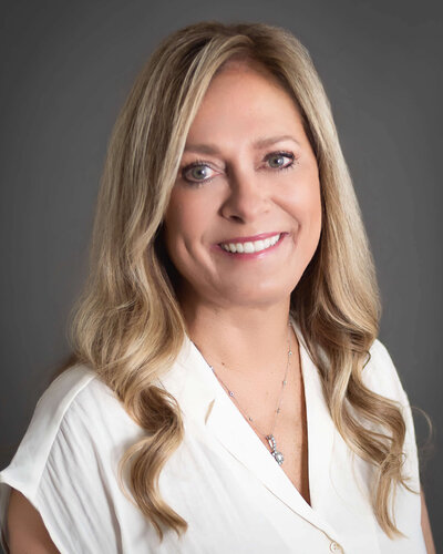 Blonde woman wearing cream shirt in professional headshot 