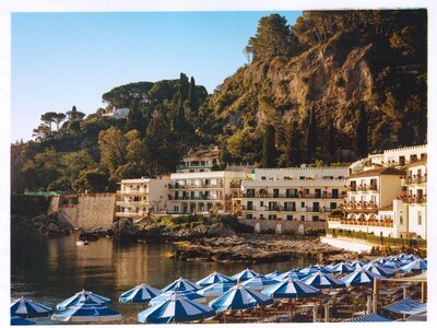 Waterside villa against mountain with blue shade umbrellas 