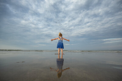 Child standing with arms outstretched on the beach, photographed by Boston family photographer Corey Flint.