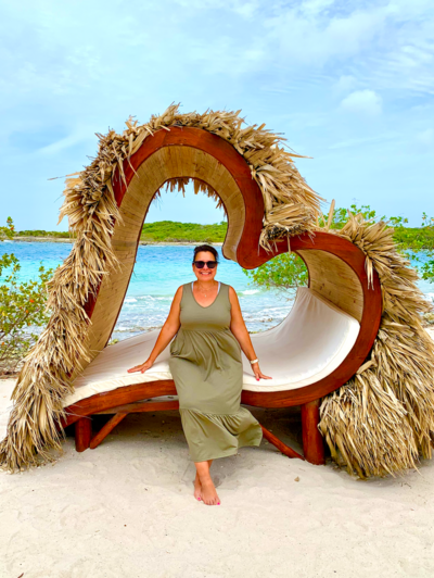female wedding planner sitting on heart-shaped lounger on beach