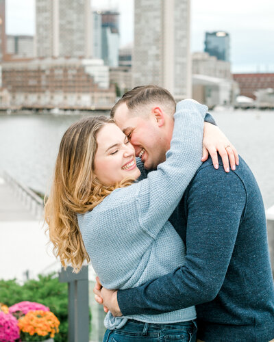 engaged couple hugging beside water