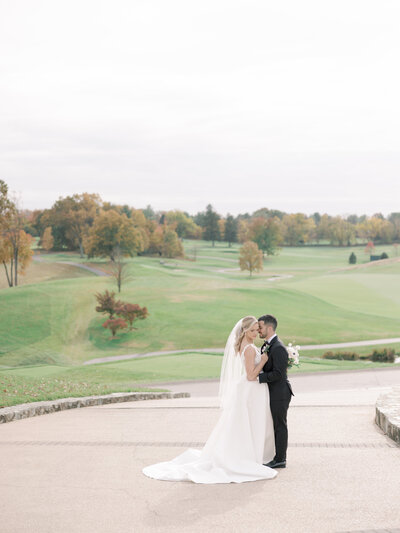 A bride and groom hug overlooking the golf course at Congressional Country Club