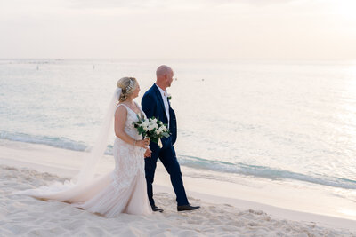 Bride and groom holding hands walking on the beach