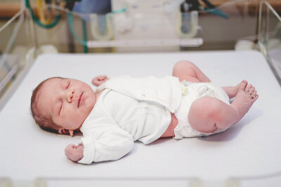 newborn baby girl posing with her parents during her newborn session