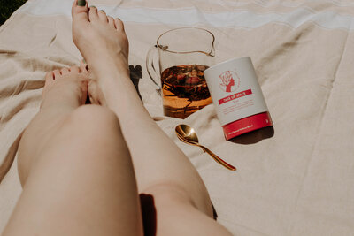 Woman dressed in white holding a teacup close to her chest, evoking sacred feminine ritual and rest.