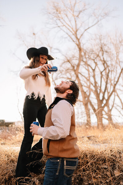 Girl pouring beer into guys mouth