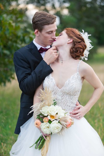 Great Gatsby wedding couple embrace in a field while almost kissing
