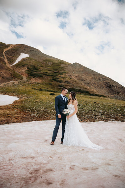 A couple kiss on a patch of snow in the Ouray mountains.