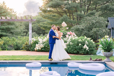Bride and Groom look at each other with love holding a clear umbrella out front a stone building at night