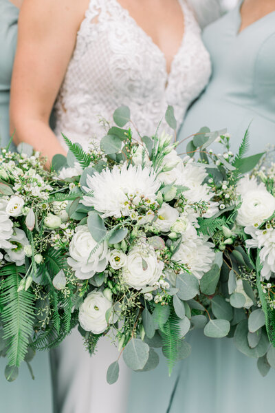 Bridal bouquets being held by a bride and bridesmaids - white, ivory, dusty green