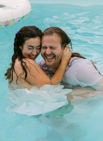 Couple embracing and laughing after jumping in the pool during their unique elopement 