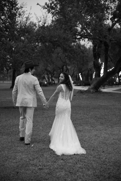 An Austin-based wedding photographer captures a bride and groom walking in front of a picturesque pond.