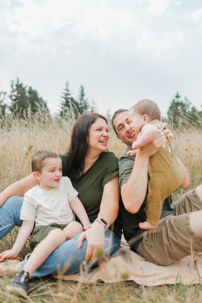 Family with two children sitting in a field, laughing together