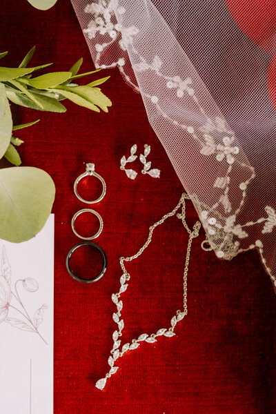 flat lay details, of the brides keepsakes, of her rings, necklace, earrings and invites. 