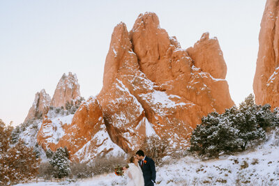 During their elopement in Colorado, ride and groom kiss in between red rocks at Garden of the Gods