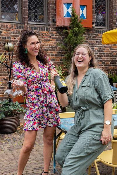 Twee meiden die een feestje vieren met een fles champagne vast 
