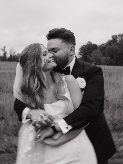 black and white photo of groom hugging bride from behind
