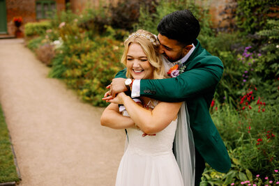 A Multi race bride and groom having a cheeky cuddle during their wedding portraits