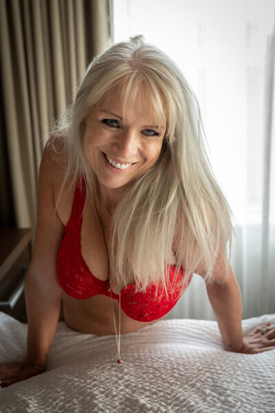 Boudoir portrait of Montana woman in red bra leaning on bed