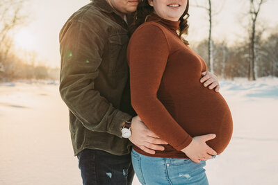 husband holds his wife's pregnant belly