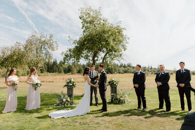 Bride and groom holding hands during a marriage ceremony in a field