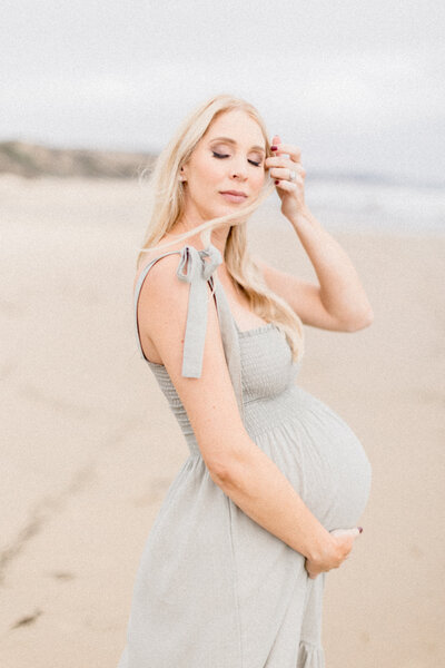 Halleigh Hill Maternity Session | Preganat woman stands on beach