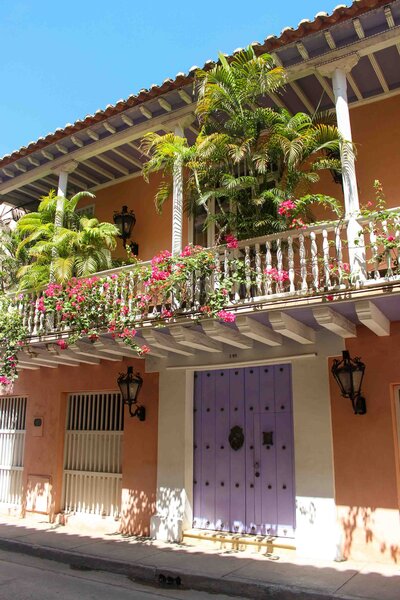Colorful colonial-style house in Cartagena, with a lilac wooden door, wrought-iron lanterns, and a bougainvillea-covered balcony ©Stephanie Dosch | theViatrix Cartagena Luxury Travel Guide