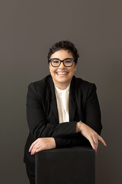 CEO of large company is posing with a blue blazer over white backdrop for his professional headshot taken by Ingrid Barnhart Photography in Austin