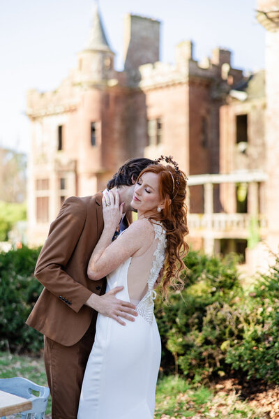 Glasgow groom kisses brides neck in front of castle
