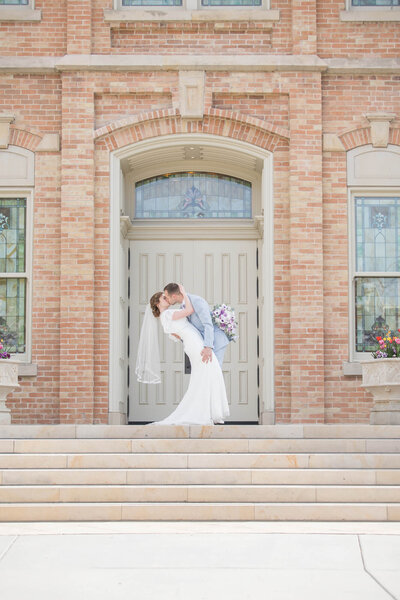 A wedding couple  enjoy a kissing dip on the steps leading up to the Provo City Center lsd temple