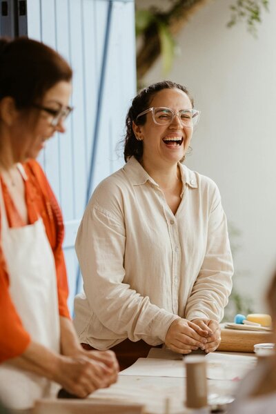 Two women smiling and talking together during a therapy session representing connection and support at Rooted & Nourished Psychotherapy