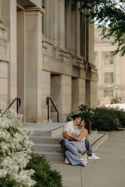 A young couple embraces one another while seated on marble steps in Iowa City, Iowa.