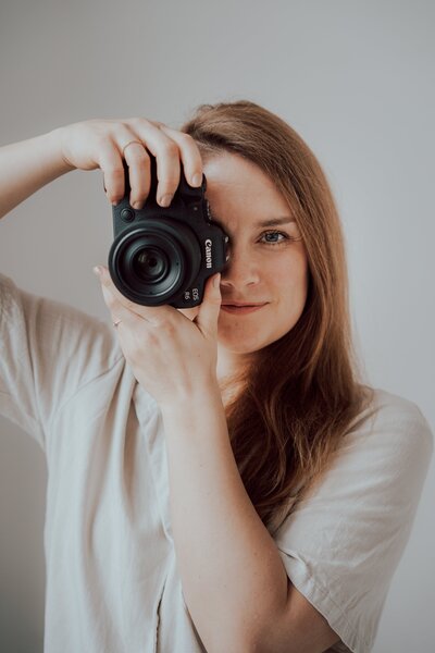 Portrait von Jule Kreher mit Canon Kamera vor ihrem Gesicht