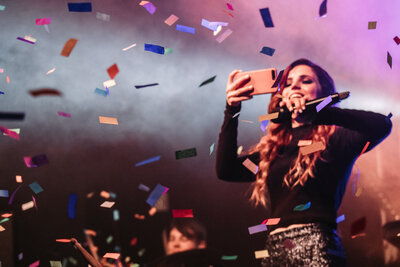 woman holding a phone taking a photo surrounded by confetti