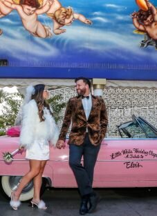 Sonya & Connor holding hands standing next to a pink cadillac