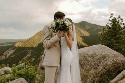 bride and groom kissing while standing outside with Colorado mountains in the background