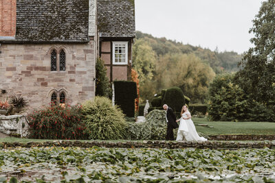 bride and groom walking alongside a large pond at wedding venue