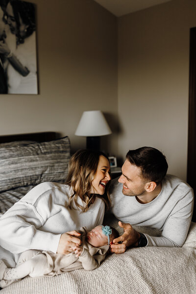 Woman and Man looking at eachother smiling with newborn baby in between them