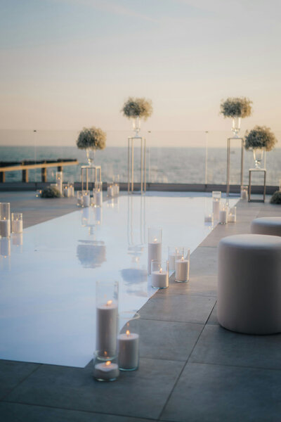 Minimalist wedding setup by the pool with candles and ocean view