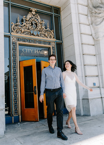 Bride and groom walking out of SF City Hall.