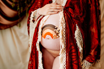 Pregnant mom holds belly, that has a rainbow painted on it
