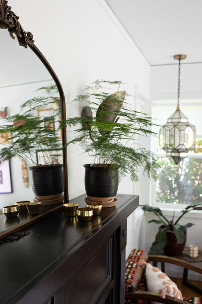 A plant on a dresser and a unique hanging light fixture, representing an example of eclectic home decor in a modern bohemian interior design. 
