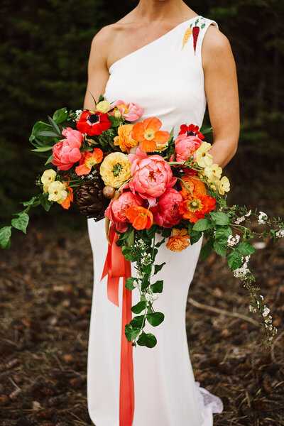 Vibrant bridal bouquet featuring peonies, poppies, butterfly ranunculus, artichokes and carrots