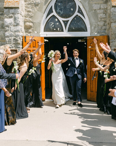 Elegant photo of a bride and groom departing the Banff Springs Hotel in a vintage Rolls-Royce, a true symbol of luxury.