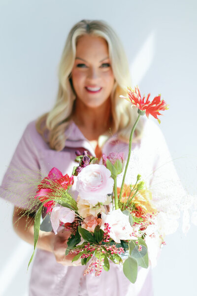 Headshot of Ashley Wallace holding a pink and green floral arrangement