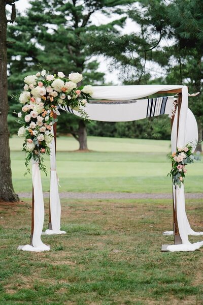 Traditional chuppah adorned with delicate white blooms and soft draped fabric, expertly crafted by Leigh Florist for an intimate wedding ceremony.