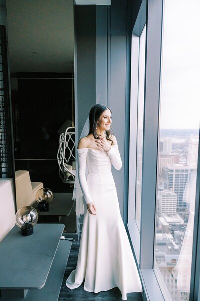 Bride looking out the window of a hotel while getting ready