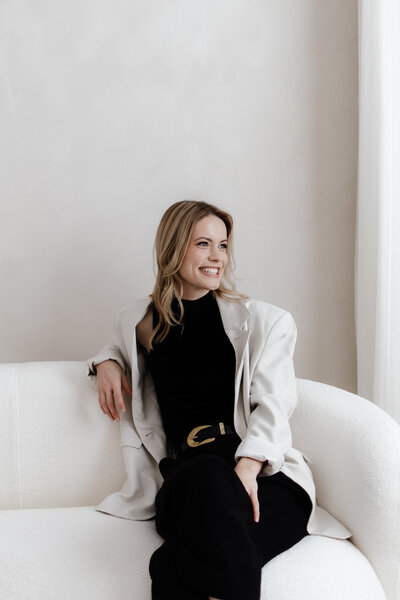 Brisbane Photographer Hannah Redman reclines in a chair and smiles toward the window - Brisbane Luxury wedding photographer