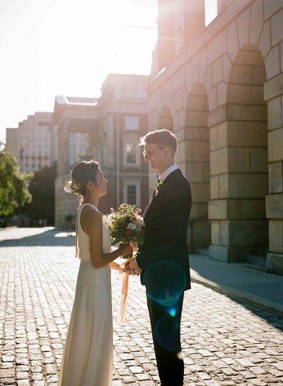 A couple facing each other in front of Osgoode Hall in Toronto on their wedding day. 