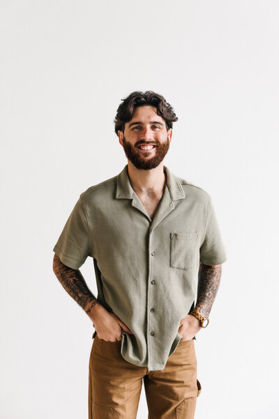 A person smiling with hand in pockets